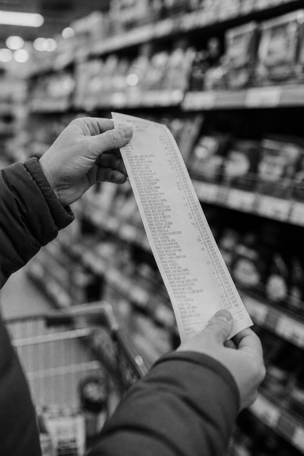 A shopper holding a grocery receipt in a supermarket aisle